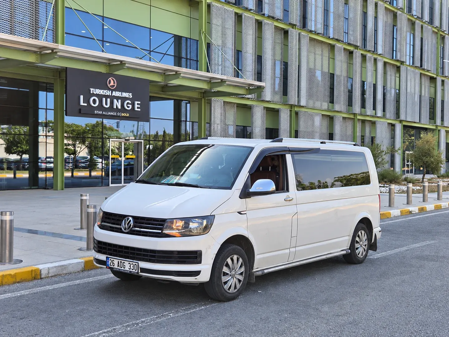 Havalimanı lounge girişi önünde beyaz Volkswagen minibüs